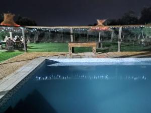 a swimming pool at night with a bench and a fence at Cabañas El Sauce in Albardón
