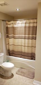 a bathroom with a toilet and a shower curtain at Lovely Guest Entire Apartment in Ottawa
