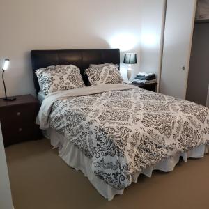 Schlafzimmer mit einem Bett mit einer schwarzen und weißen Bettdecke in der Unterkunft Lovely Guest Entire Apartment in Ottawa