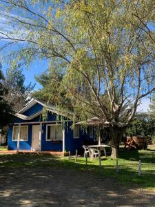 une maison bleue avec une table de pique-nique et un arbre dans l'établissement Cabañas el Yacal, à El Bolsico