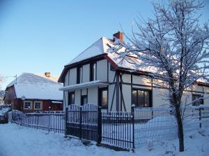ein weißes Haus mit einem Zaun im Schnee in der Unterkunft Agroturystyka W Jabłoniowym Sadzie in Jeżyce