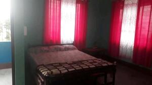 a bedroom with a bed with red curtains and a window at Pandeys Homestay Kalimpong in Kalimpong