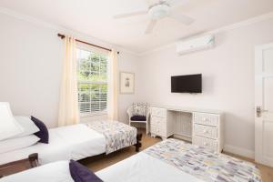 - une chambre avec 2 lits et une télévision à écran plat dans l'établissement Jamaica Time Driftwood at Sea Palms 3BR 3BA Condo in Ocho Rios with Pool and Beach Front with Views ONLY 10 Mins from Ochi Intl Airport Direct flight from Miami, à St Mary