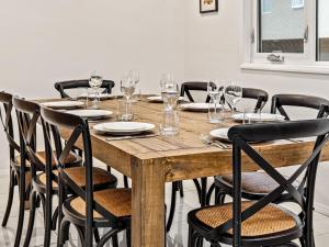 una mesa de madera con sillas y copas de vino. en Snoqualmie 3 2 Cobbodah St, en Jindabyne