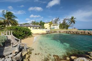 a house on the beach with a pool of water at Jamaica Time Driftwood at Sea Palms 3BR 3BA Condo in Ocho Rios with Pool and Beach Front with Views ONLY 10 Mins from Ochi Intl Airport Direct flight from Miami in St Mary