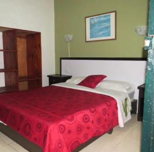 a bedroom with a large bed with a red blanket at Hotel Belen in Popayan