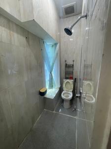 a bathroom with a toilet and a shower with a window at Bagus house in Pekanbaru