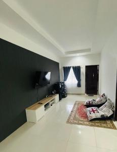 uma sala de estar com um sofá e uma televisão na parede em Bagus house em Pekanbaru