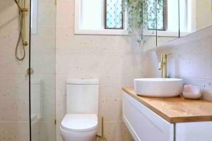 uma casa de banho com um lavatório, um WC e uma janela. em Bluebell Cottage em Beechmont