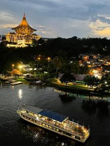 a boat in the water in front of a building at Riverbank suites unit 405 in Kuching