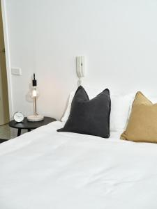 a white bed with two black pillows on it at Chic Urban Loft in Prime Location in Melbourne