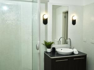 a bathroom with a sink and a glass shower at Chic Urban Loft in Prime Location in Melbourne