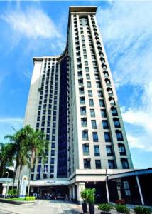 un edificio alto con una palmera delante de él en Suite Congonhas - FLAT Aeroporto Congonhas, en São Paulo