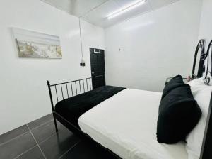 a bedroom with a bed with white sheets and black pillows at Homestay CikPuteh Gunong, Bachok in Bachok