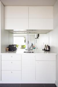 a white kitchen with white cabinets and a sink at The Hamptons in Kaikoura