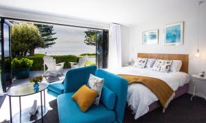 a bedroom with a bed and a couch and chairs at The Hamptons in Kaikoura