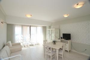 a white living room with a table and a tv at Villa Allegra in Kavarna