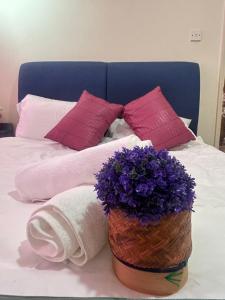 a basket of purple flowers on a bed with pillows at Riverbank suites unit 405 in Kuching