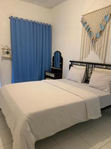 a bedroom with a large bed with a blue curtain at Silverin Bajawa in Bajawa