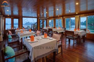 a restaurant with white tables and chairs and windows at Minh Hằng Cruise in Ha Long