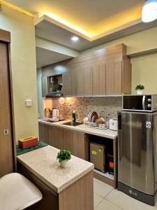 Horizons 101 Condo in Cebu City في مدينة سيبو: مطبخ مع دواليب خشبية وثلاجة حديد قابلة للصدأ