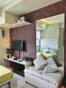 Horizons 101 Condo in Cebu City في مدينة سيبو: غرفة نوم بسريرين ومكتب فيه شاشة