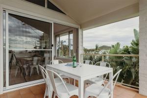 een witte tafel en stoelen op een veranda met een raam bij Baybreeze 18 Tomaree Road WiFi Air Conditioning Kitchenette in Shoal Bay