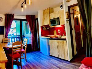 cocina con paredes rojas, armarios de madera y mesa en Appartement Châtel, 2 pièces, 5 personnes - FR-1-676-171 en Châtel