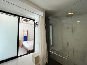 ein Bad mit einer Dusche und eine Glastür mit einem Schlafzimmer in der Unterkunft The Snug Airportel - Phuket Airport in Nai Yang Beach