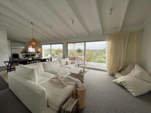 ein Wohnzimmer mit weißen Möbeln und einem großen Fenster in der Unterkunft Rye Beach House - Sunset Views in Rye