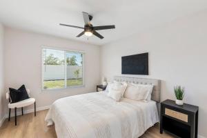 a white bedroom with a bed and a ceiling fan at Vineyard Chic Oasis: Modern Elegance near Temecula Wineries in Temecula