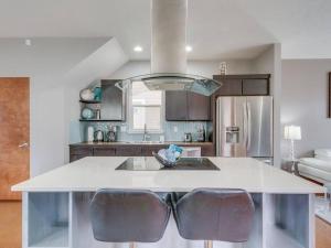 a kitchen with a white island with two leather chairs at Brand New Downtown Modern 5 Beds, 3 Full Baths Vermont Avenue, Boise in Boise
