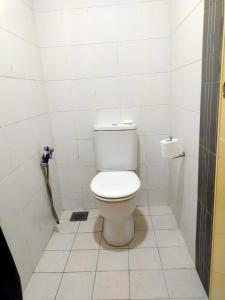 a bathroom with a toilet in a white tiled room at Reen's Cosy Place in Cyberjaya