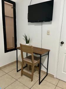 a wooden table with a chair and a television on a wall at Apartamentos Trebol in Comayagua