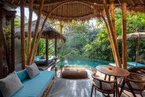 a resort with a pool with chairs and a table at Aksari Resort Ubud by Ini Vie Hospitality in Tegalalang