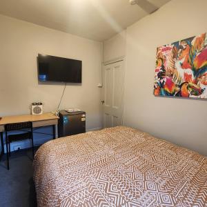 a bedroom with a bed and a desk and a flat screen tv at 50 Green St Windsor in Melbourne