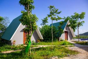 uma casa branca com um telhado verde e árvores em Sabay Farm em Kampot