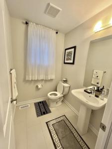 a white bathroom with a toilet and a sink at Spacious,comfy house,less than 15 mins to Niagara Falls in Thorold