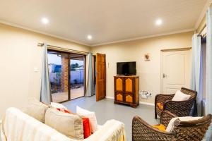 ein Wohnzimmer mit Sofa, Sesseln und Fernseher in der Unterkunft Gasteria Cottage in Mossel Bay