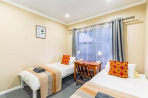 ein Zimmer mit zwei Betten und einem Fenster mit einem Schreibtisch in der Unterkunft Gasteria Cottage in Mossel Bay