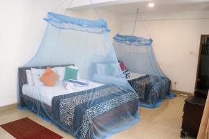 a bedroom with two beds with blue drapes at Resort Beam in Kandy