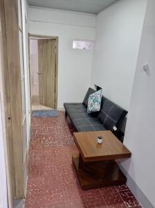 ein Wohnzimmer mit einem schwarzen Sofa und einem Tisch in der Unterkunft Coliving La Rebeca Pereira in Pereira