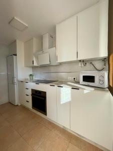 een witte keuken met witte kasten en een magnetron bij Apartamento El Portil, Playas del Sur in El Portil