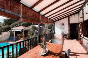 une terrasse avec une table en bois et une piscine dans l'établissement Villa T4 - Bleu Mer Caraïbes, à Case-Pilote