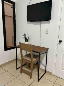 escritorio de madera con silla y TV en la pared en Apartamentos Trebol, en Comayagua