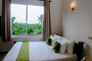 Un dormitorio con una cama con una ventana grande. en Kadolana Villa, en Mirissa
