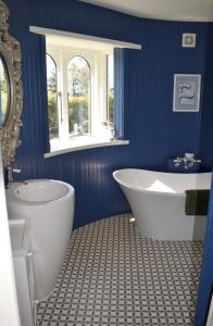 niebieska łazienka z wanną, toaletą i umywalką w obiekcie Kingsdown Manor B&B Timaru w mieście Timaru