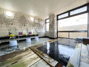 a large bathroom with a pool of water in it at Masuya Ryokan in Nozawa Onsen