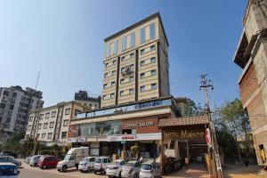een hoog gebouw met auto's geparkeerd op een parkeerplaats bij The Sky Imperial Hotel The Maison in Anand