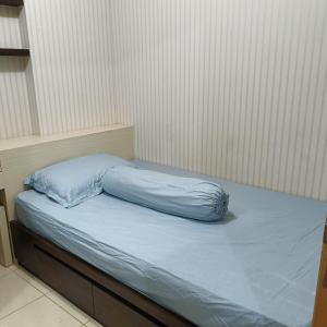 un letto con una coperta blu sopra di Apartemen Pakuwon Educity yale a Surabaya